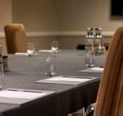Conference table set with notepads, pens, glasses, and bottled water