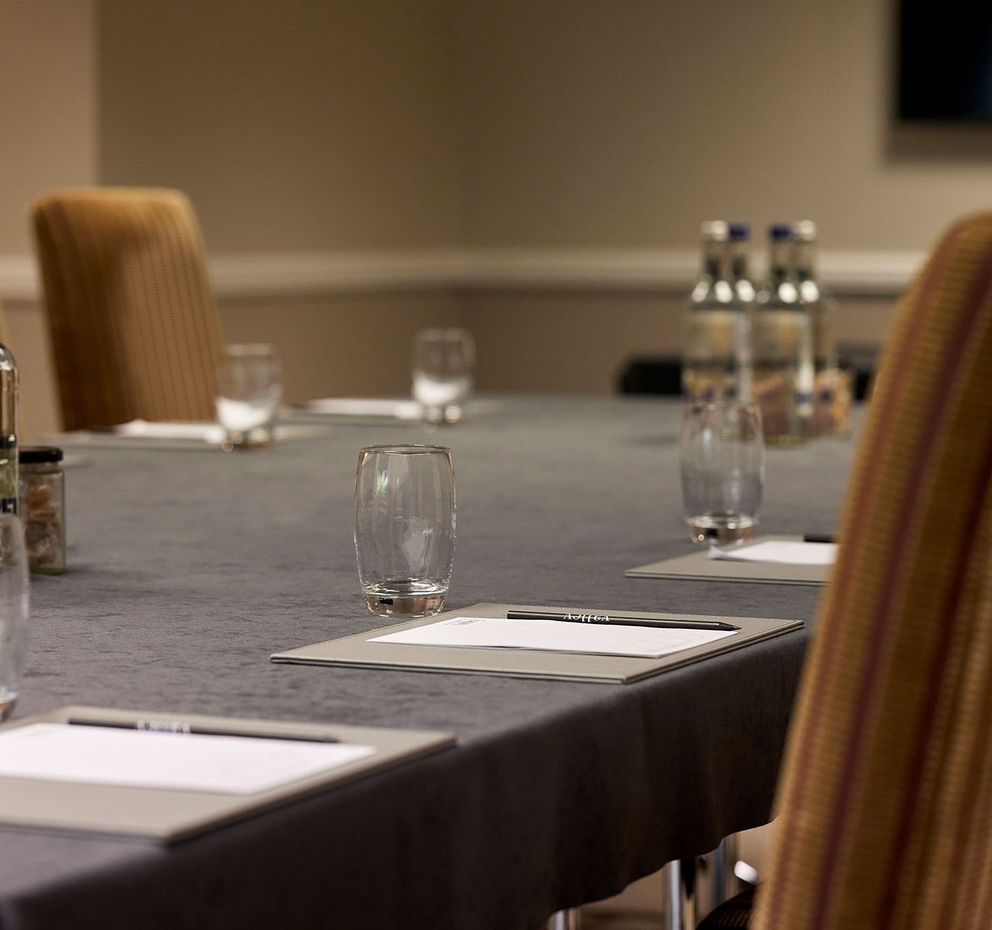 Conference table set with notepads, pens, glasses, and bottled water