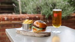 Burger with fries and a glass of beer on an outdoor table