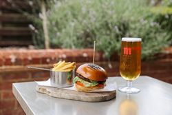Burger with fries and a glass of beer on an outdoor table