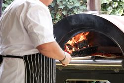 Chef placing pizza in a wood-fired oven