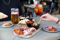 Charcuterie board with assorted meats, olives, and drinks on an outdoor dining table