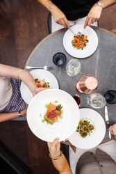 Top view of people dining at a restaurant, sharing a plated gourmet dish
