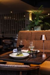 Elegant restaurant table set with gourmet dishes, wine glasses, and a modern lamp.