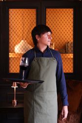 Waiter holding a tray with a glass of red wine in a cozy, warmly lit room