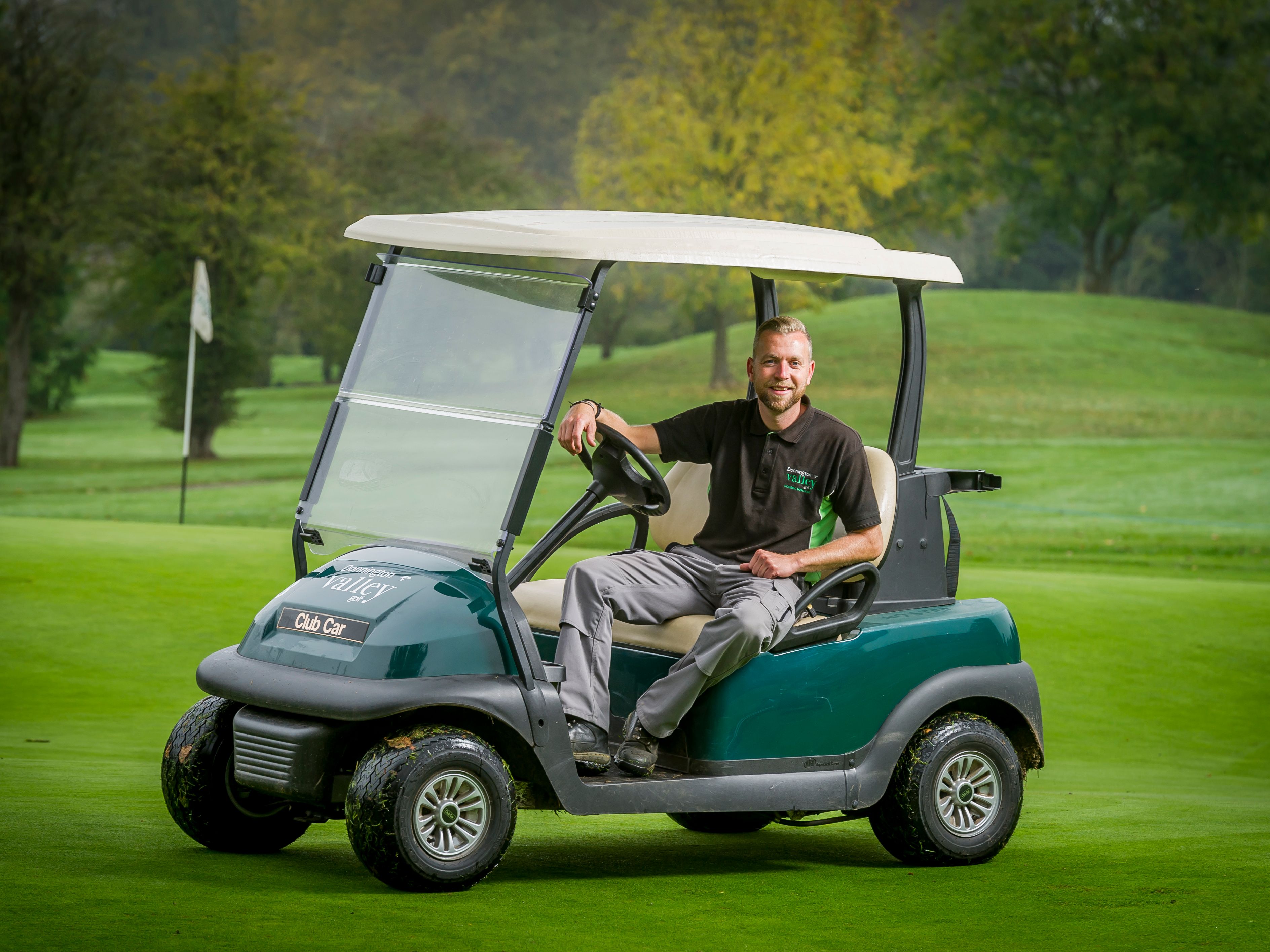 Man sitting in a golf cart on a green golf course