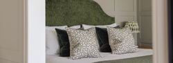 Elegant bedroom with a textured green headboard and decorative pillows.