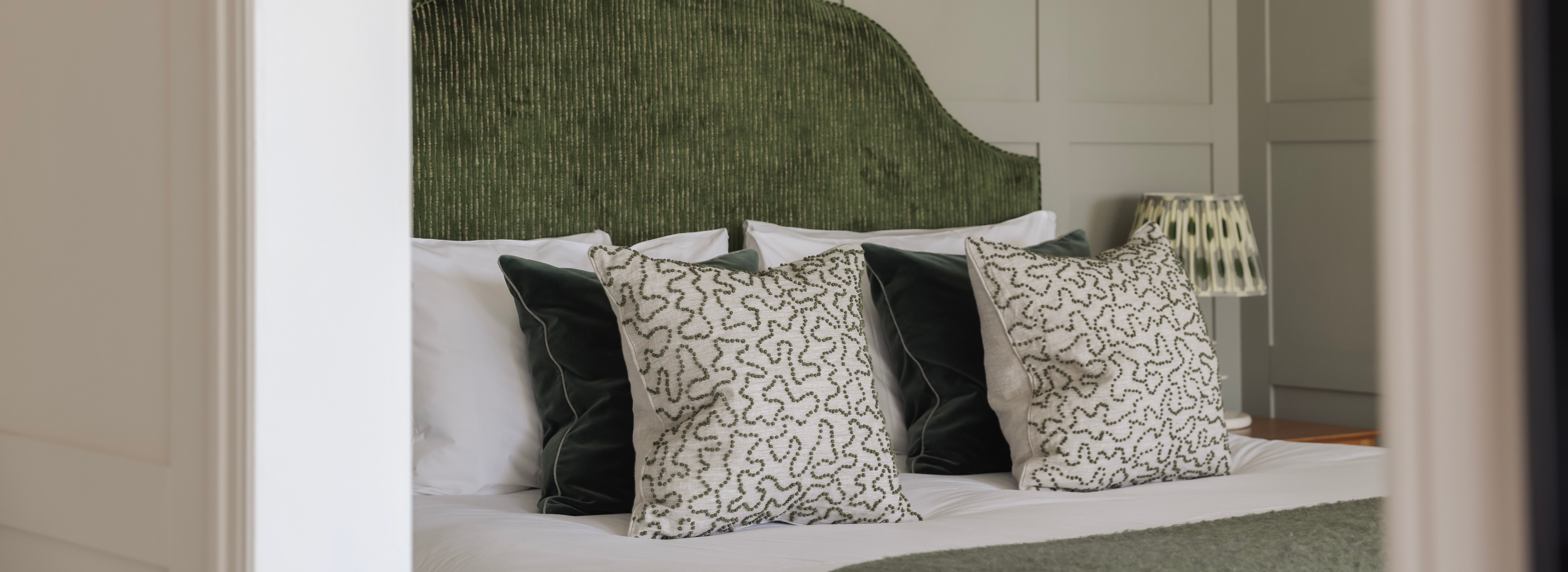 Elegant bedroom with a textured green headboard and decorative pillows.