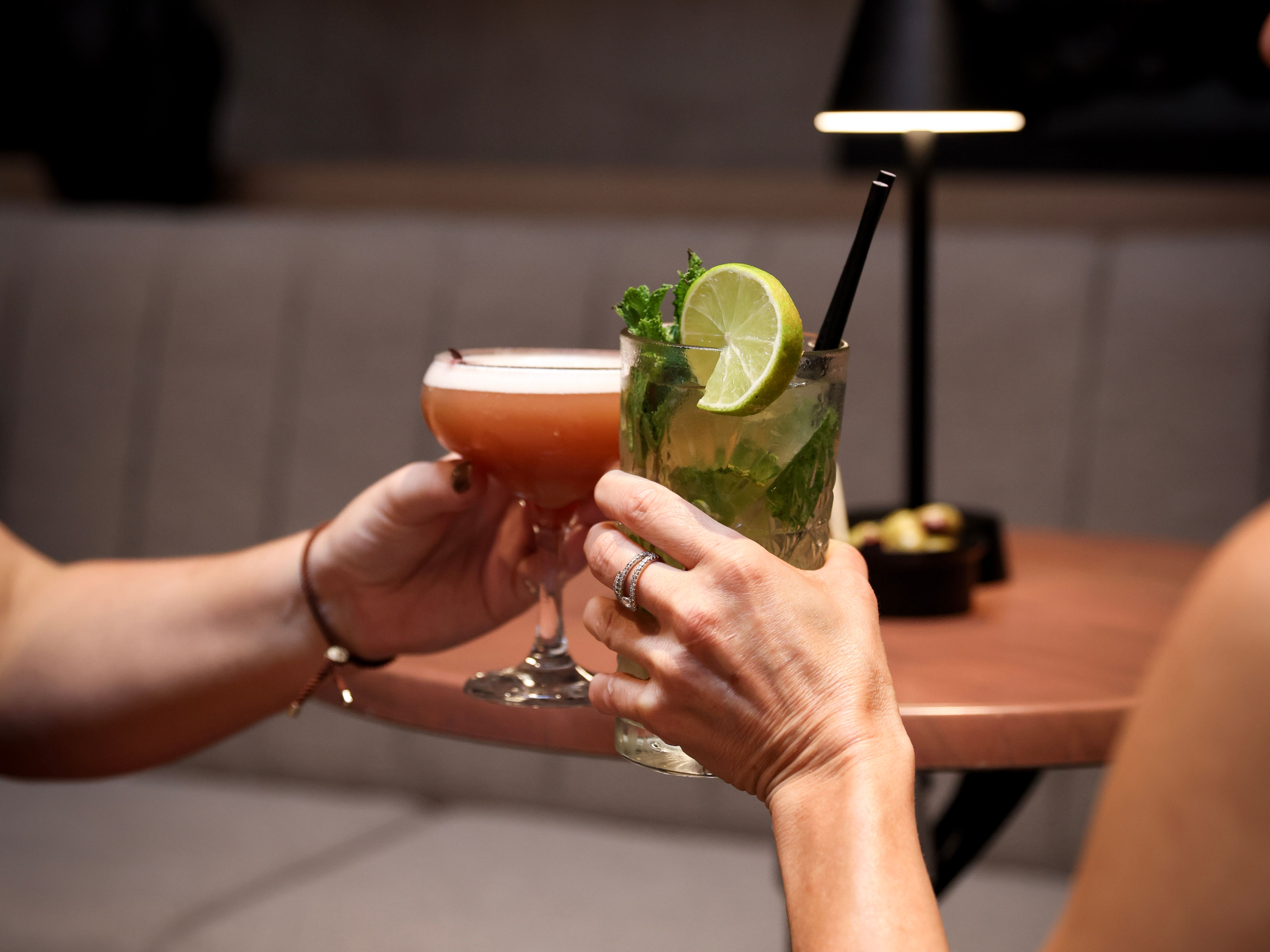 Two people clinking cocktails in a dimly lit lounge setting