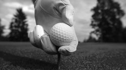 Close-up of a gloved hand placing a golf ball on a tee