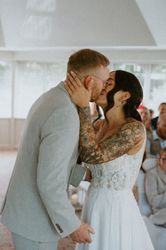 Tattooed bride and groom share a kiss during their wedding ceremony.