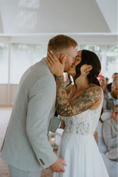 Tattooed bride and groom share a kiss during their wedding ceremony.