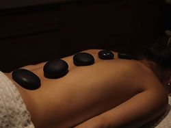 Person receiving a hot stone massage with smooth stones placed along their back