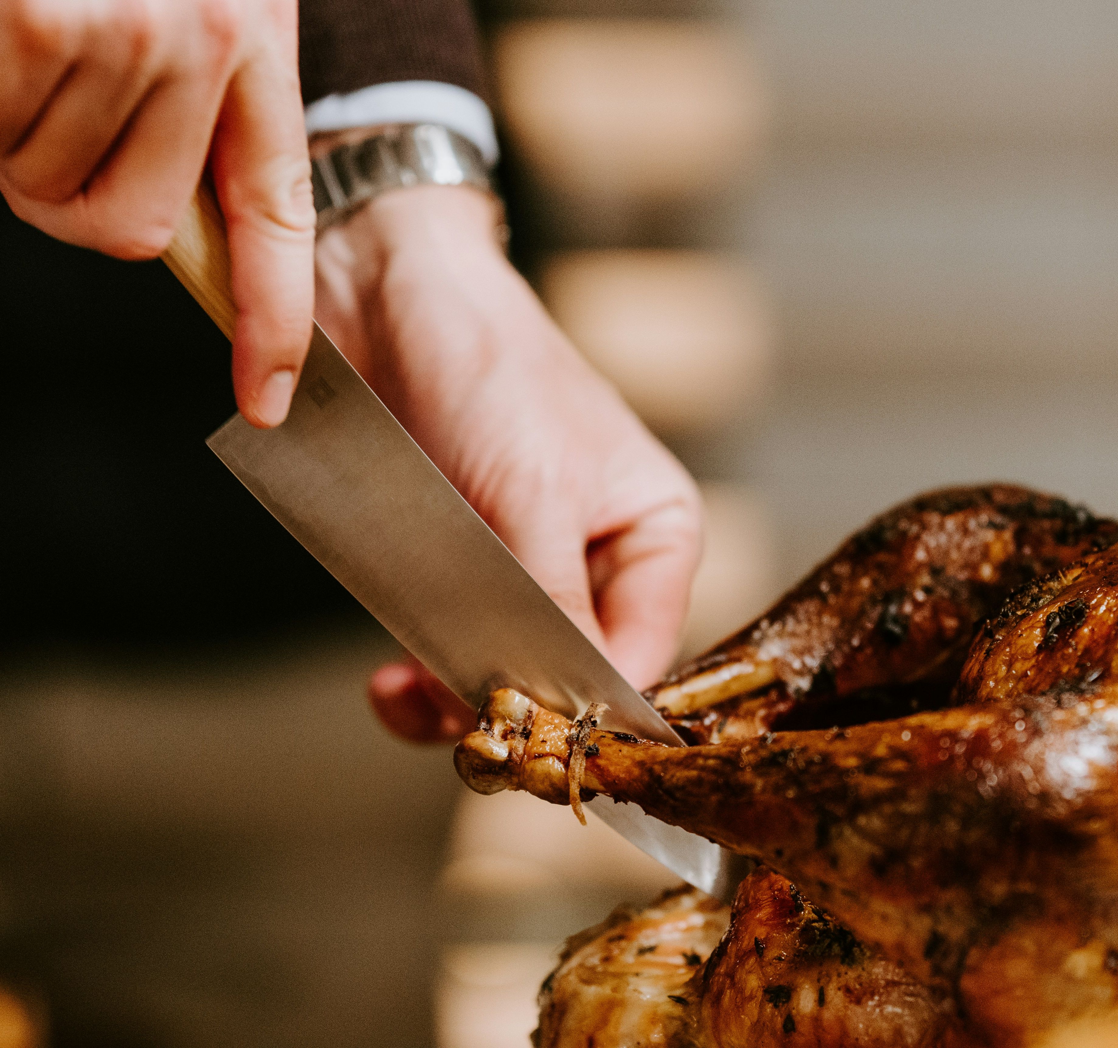 Person carving a roasted turkey with a large knife