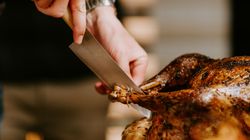 Person carving a roasted turkey with a large knife
