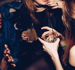 People laughing and holding drinks at a party or nightclub.