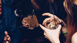 People laughing and holding drinks at a party or nightclub.