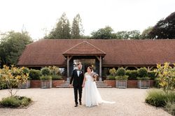 Bride and groom holding hands and smiling at each other in front of a rustic barn venue.