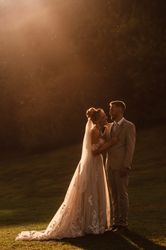 Bride and groom embracing outdoors in warm sunset light