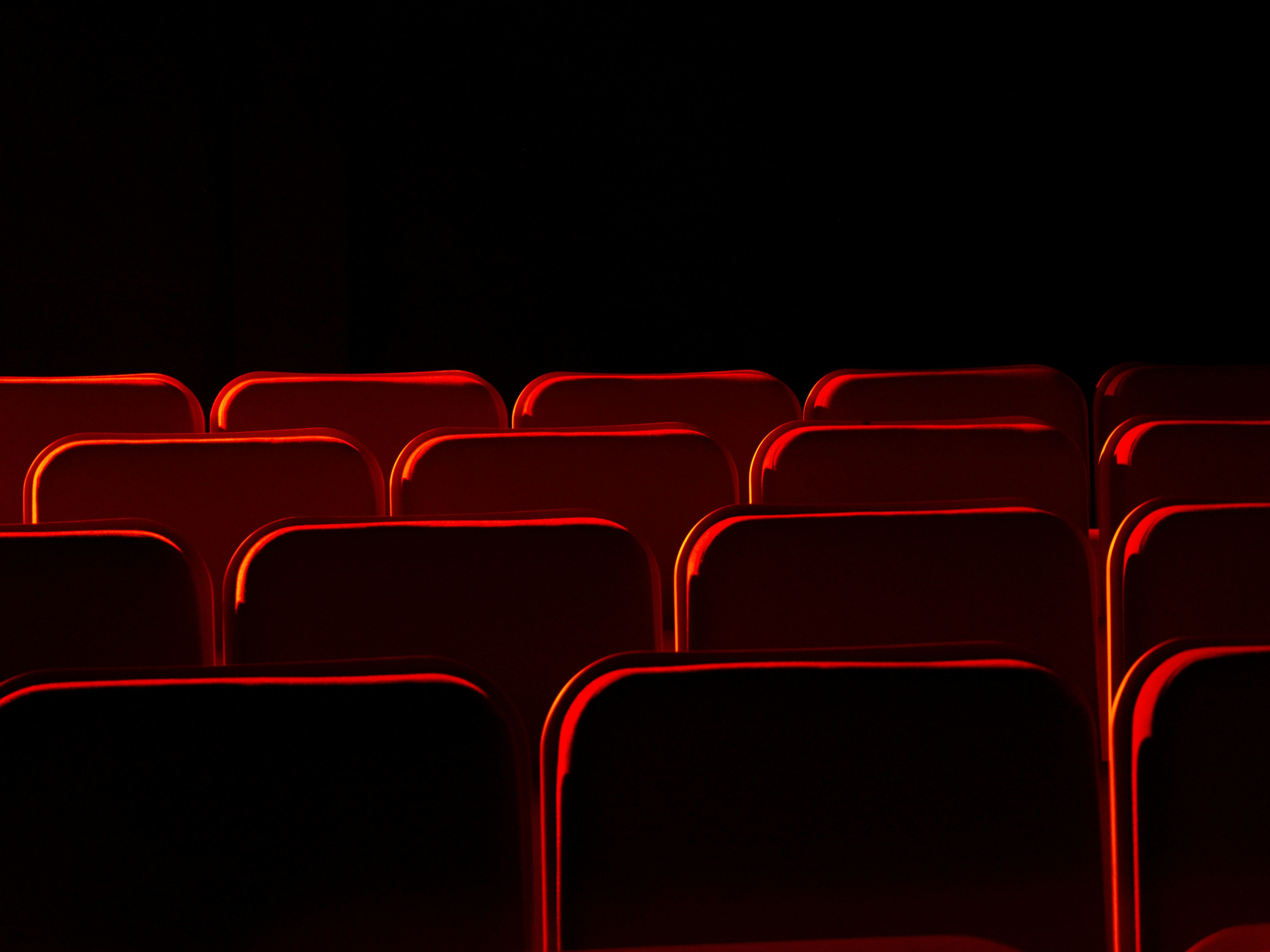 Empty red theater seats in a dark room