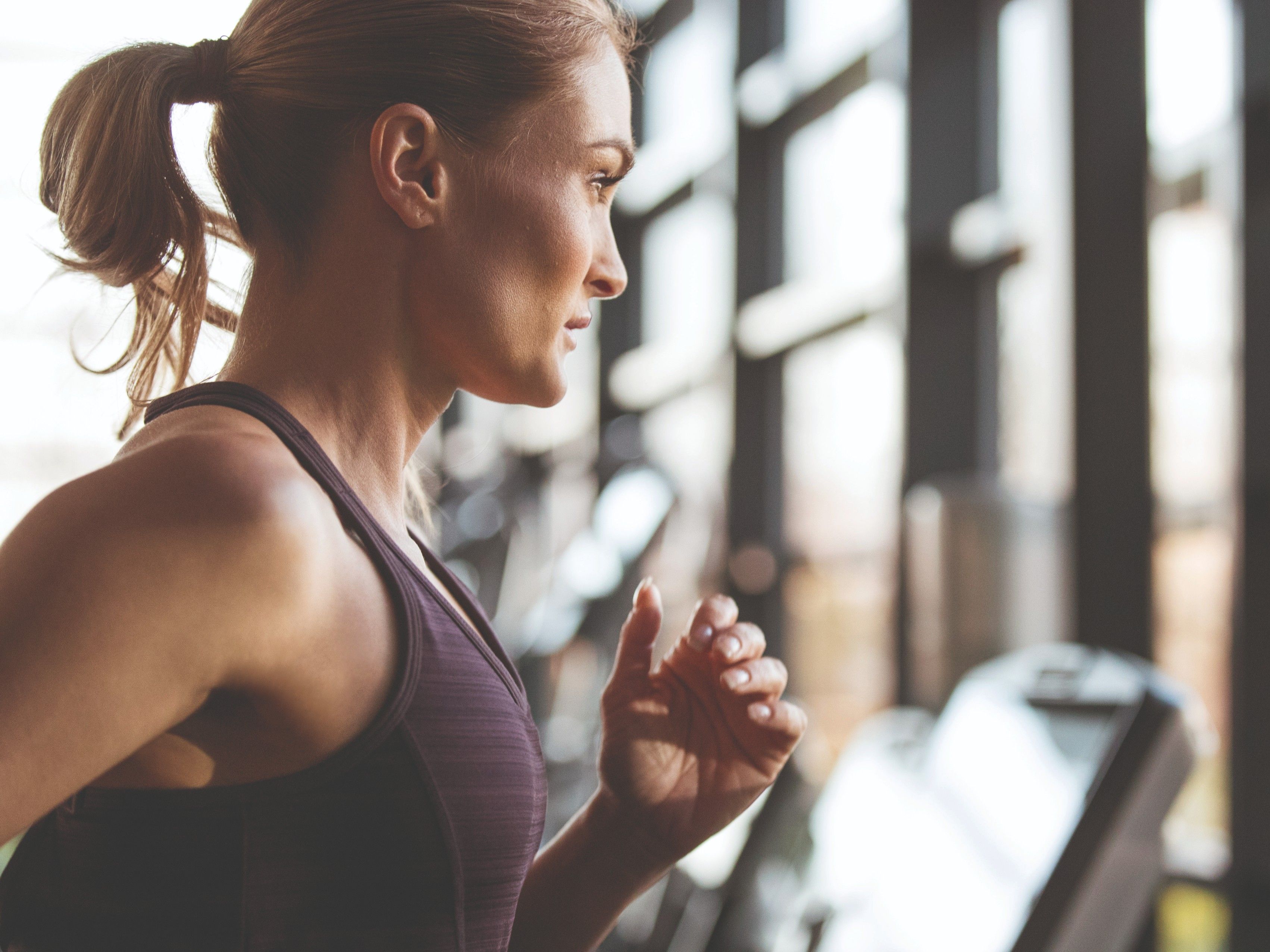Woman running on a treadmill in a gym, profile view