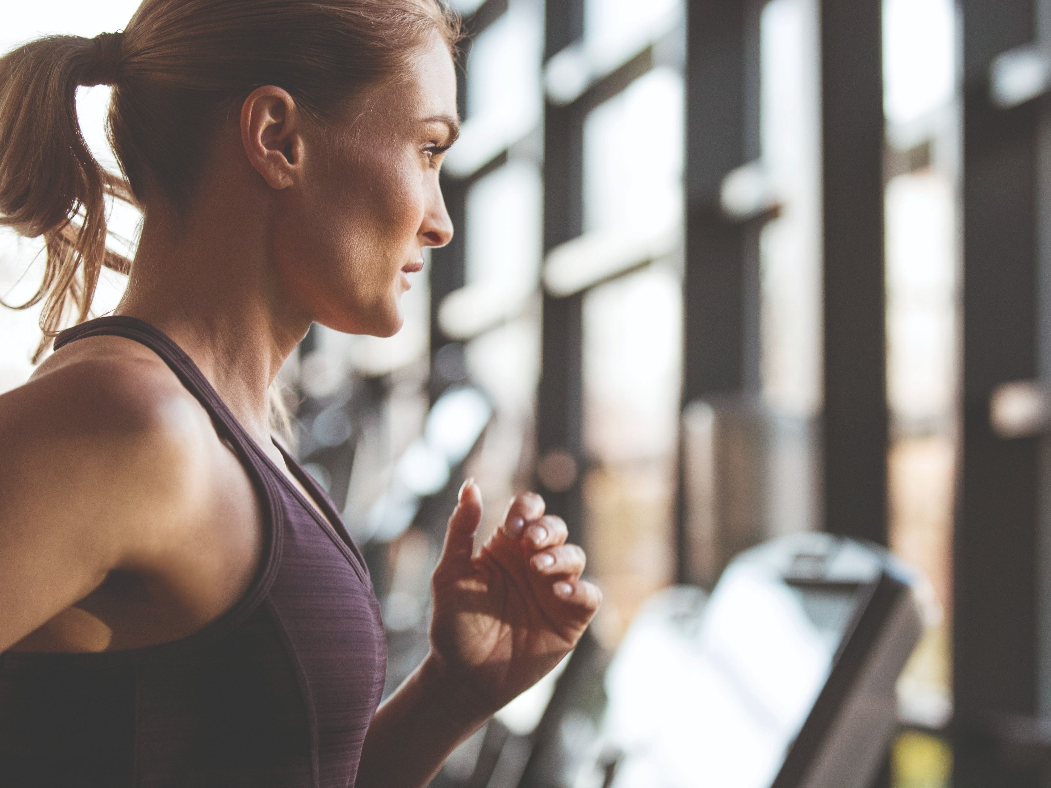 Woman running on a treadmill in a gym, profile view