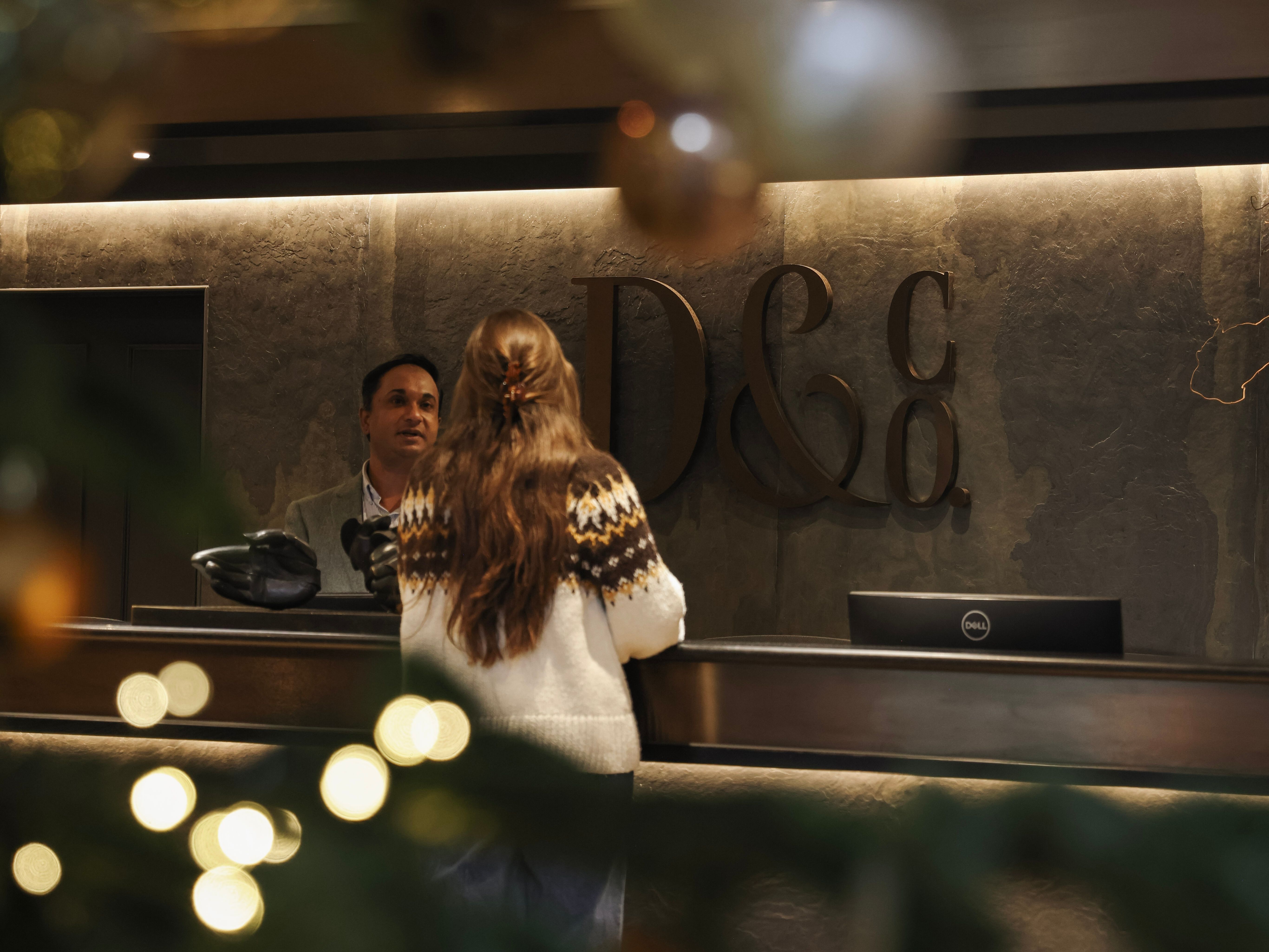 A woman at a hotel reception desk decorated for the holidays, with Christmas tree ornaments and lights in the foreground.