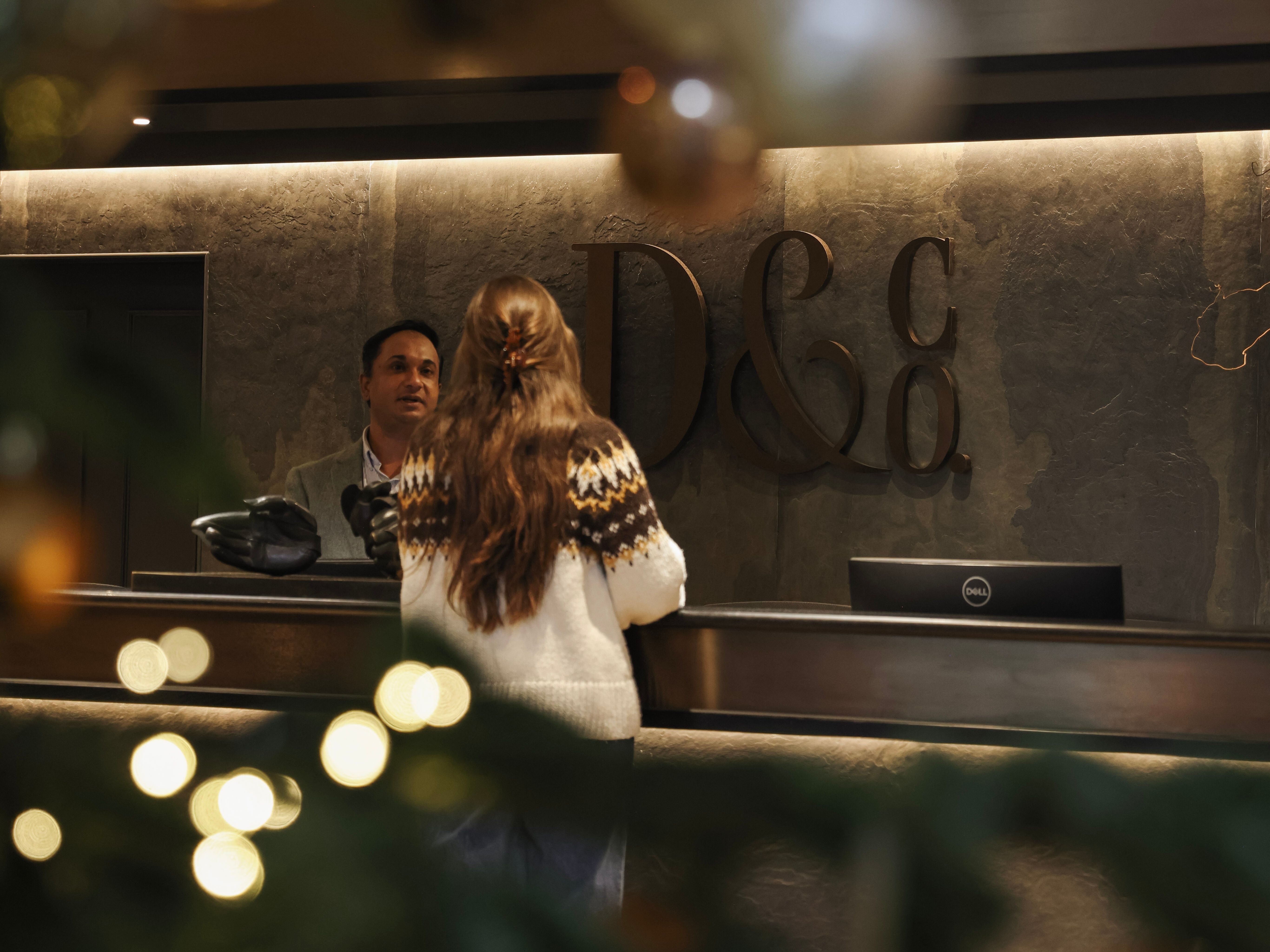 A woman at a hotel reception desk decorated for the holidays, with Christmas tree ornaments and lights in the foreground.