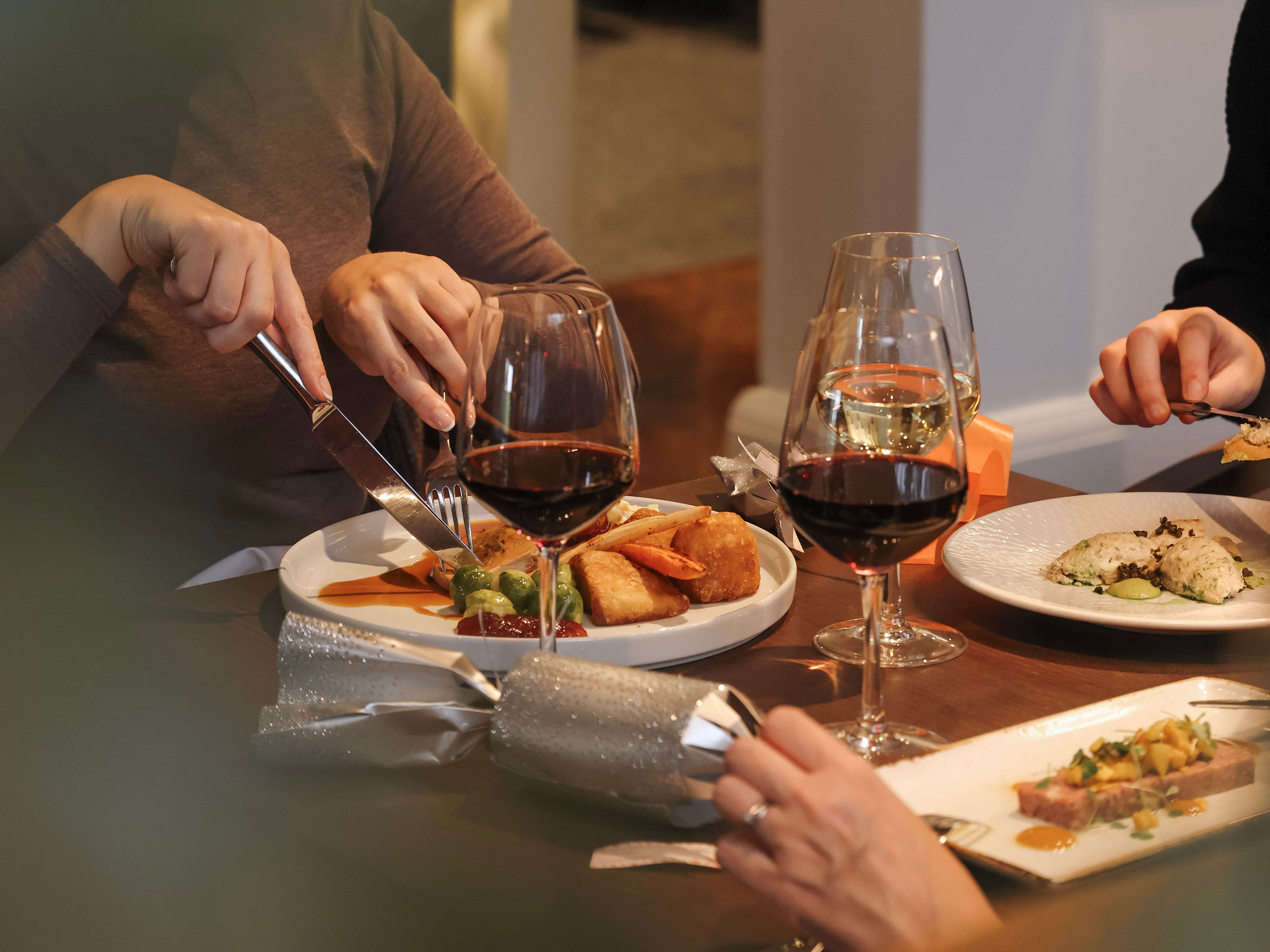 People dining at a table with wine glasses and plated meals.