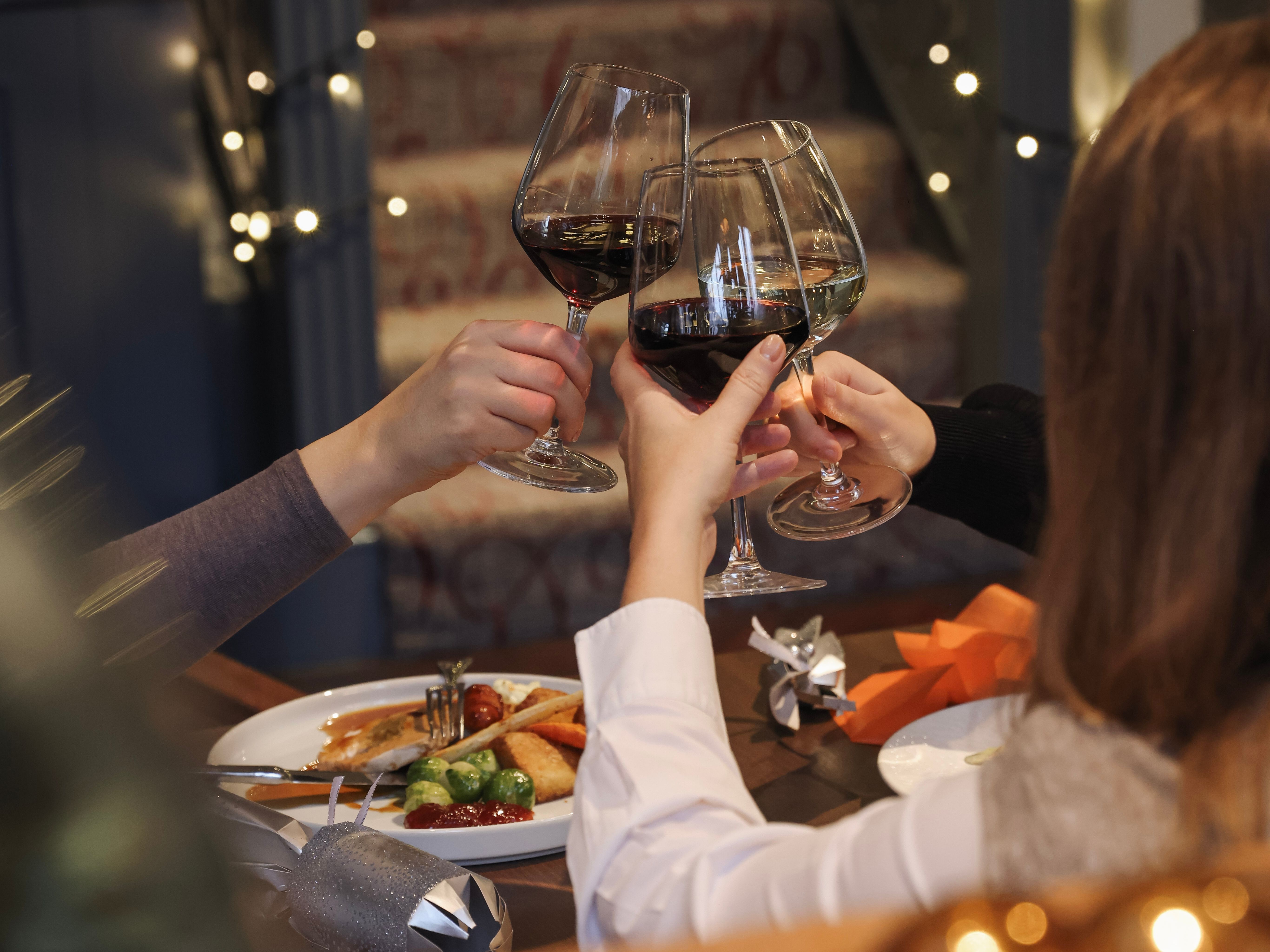 Three people clinking wine glasses at a festive dinner table