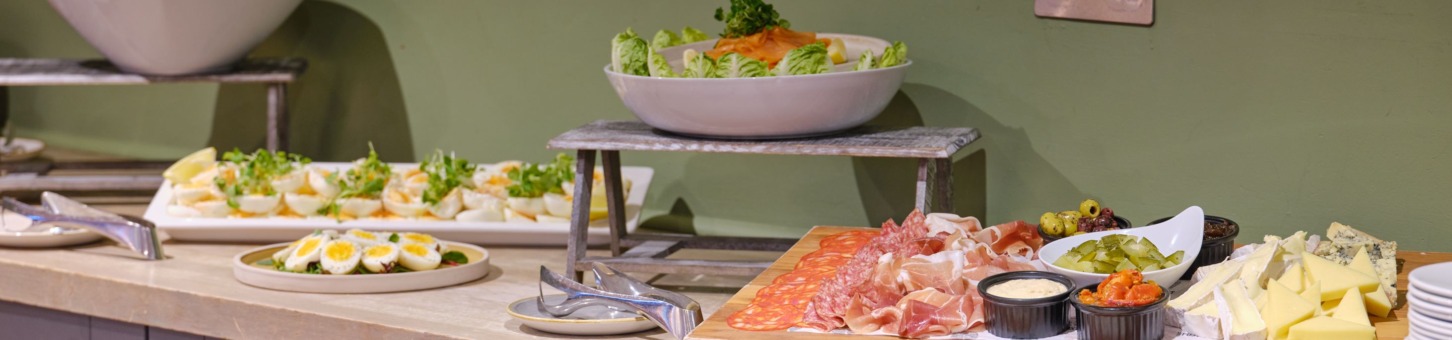 Buffet table with salad, deviled eggs, cold cuts, cheeses, and dips
