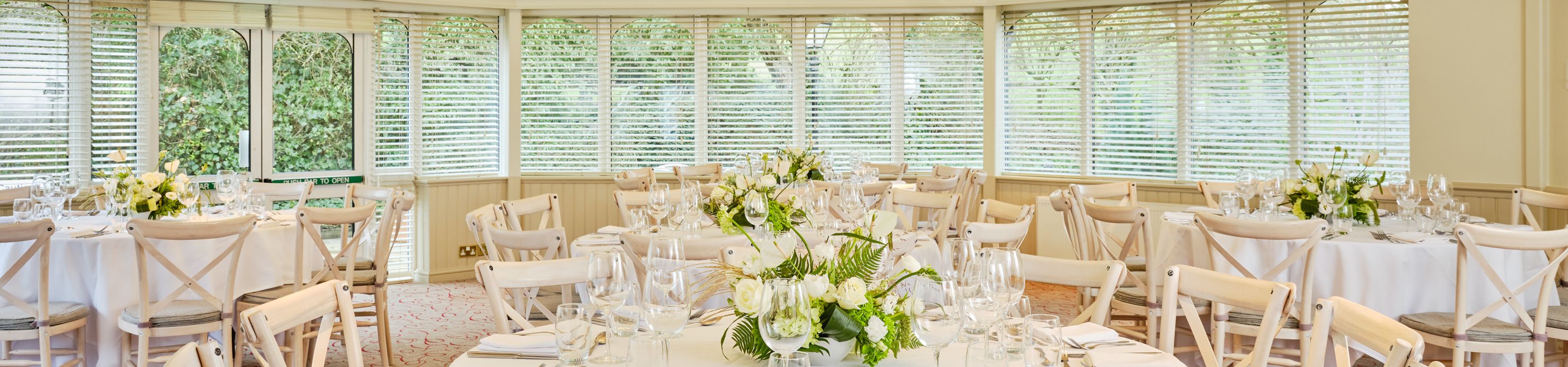 Elegant conference or banquet room set up with round tables, white linens, and floral centerpieces