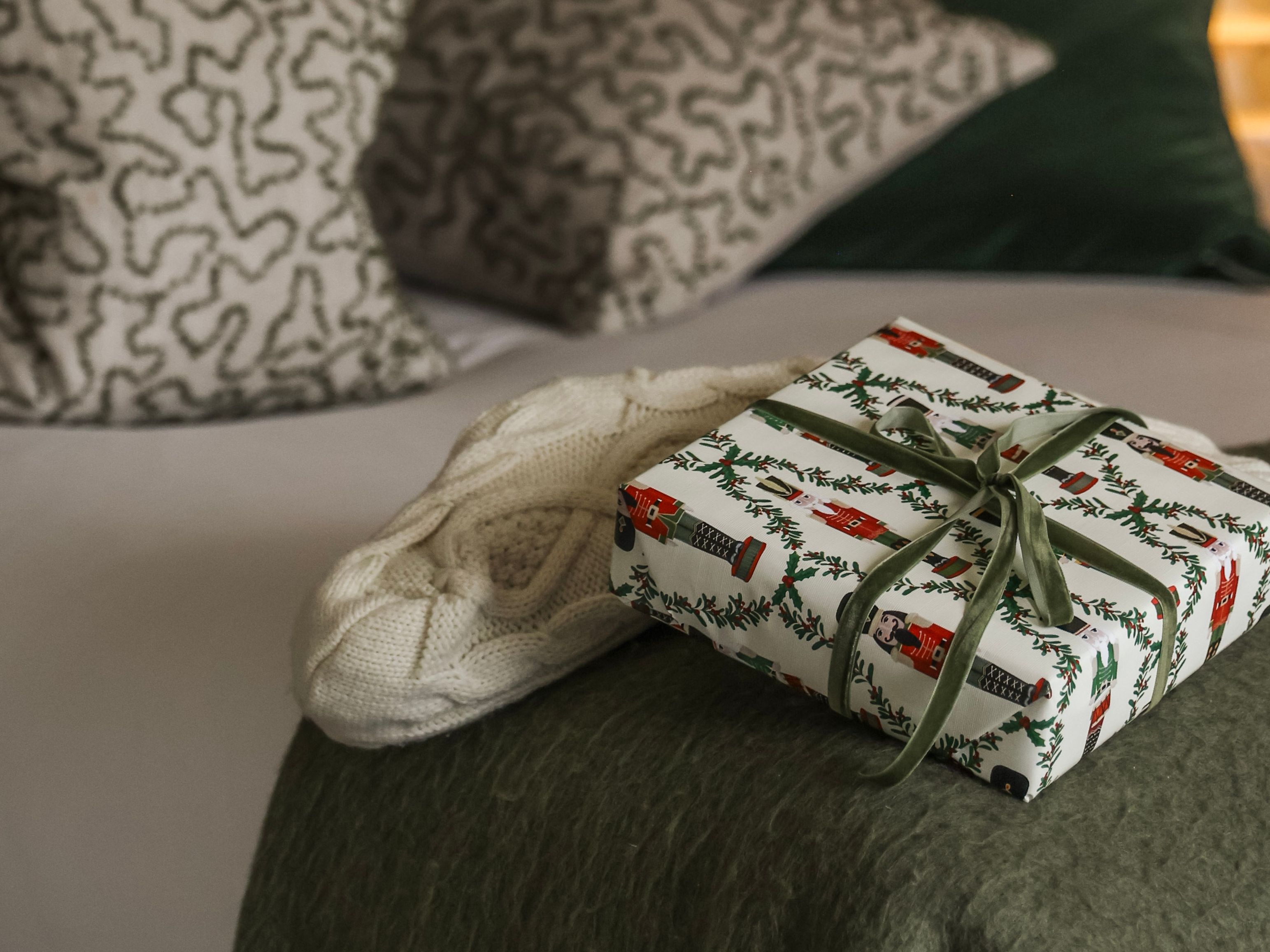 Cozy bedroom with decorative pillows, a green throw, and a wrapped gift on the bed.