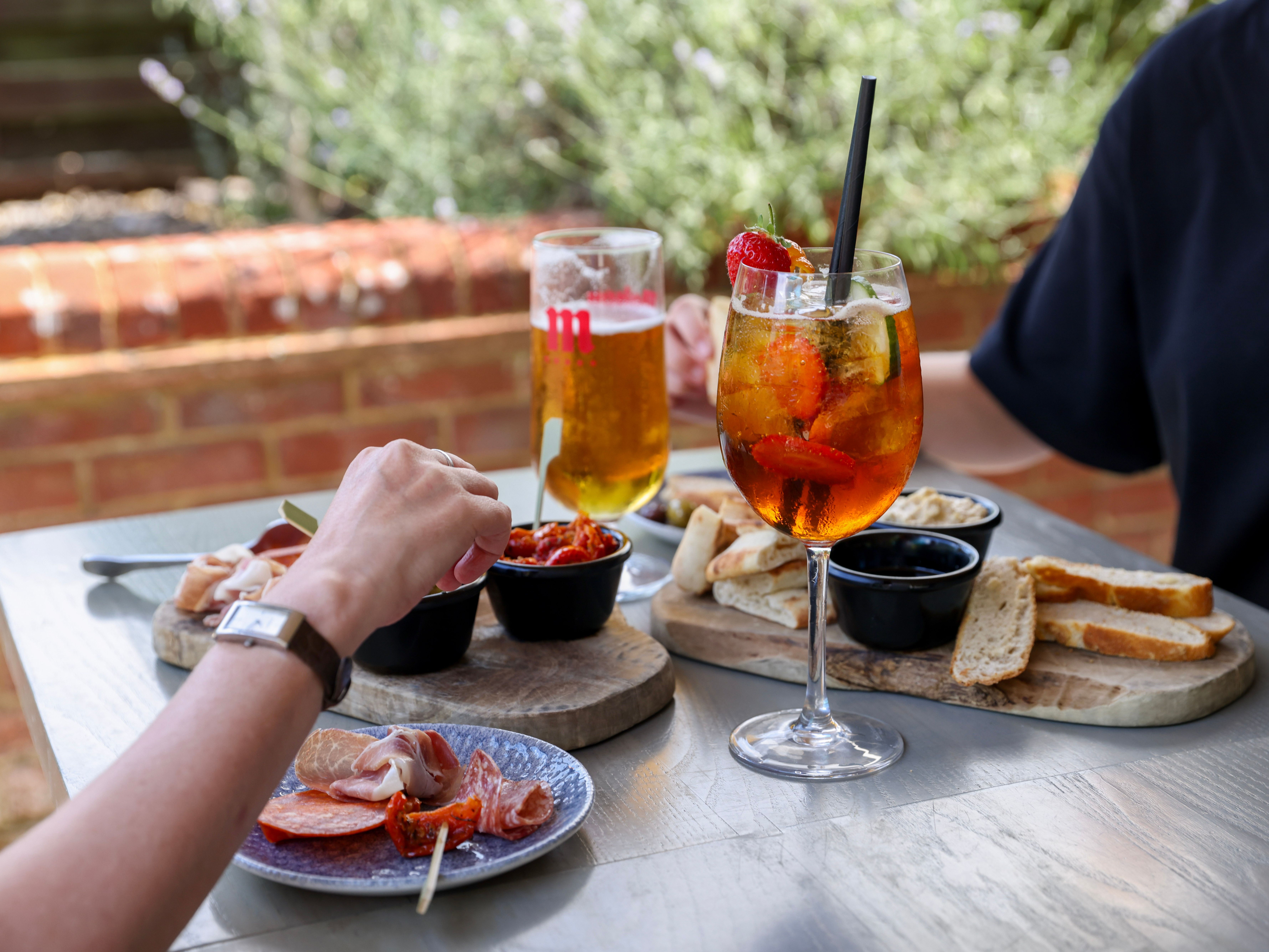Sharing tapas and drinks at an outdoor table with a fruit spritz and a pint of beer