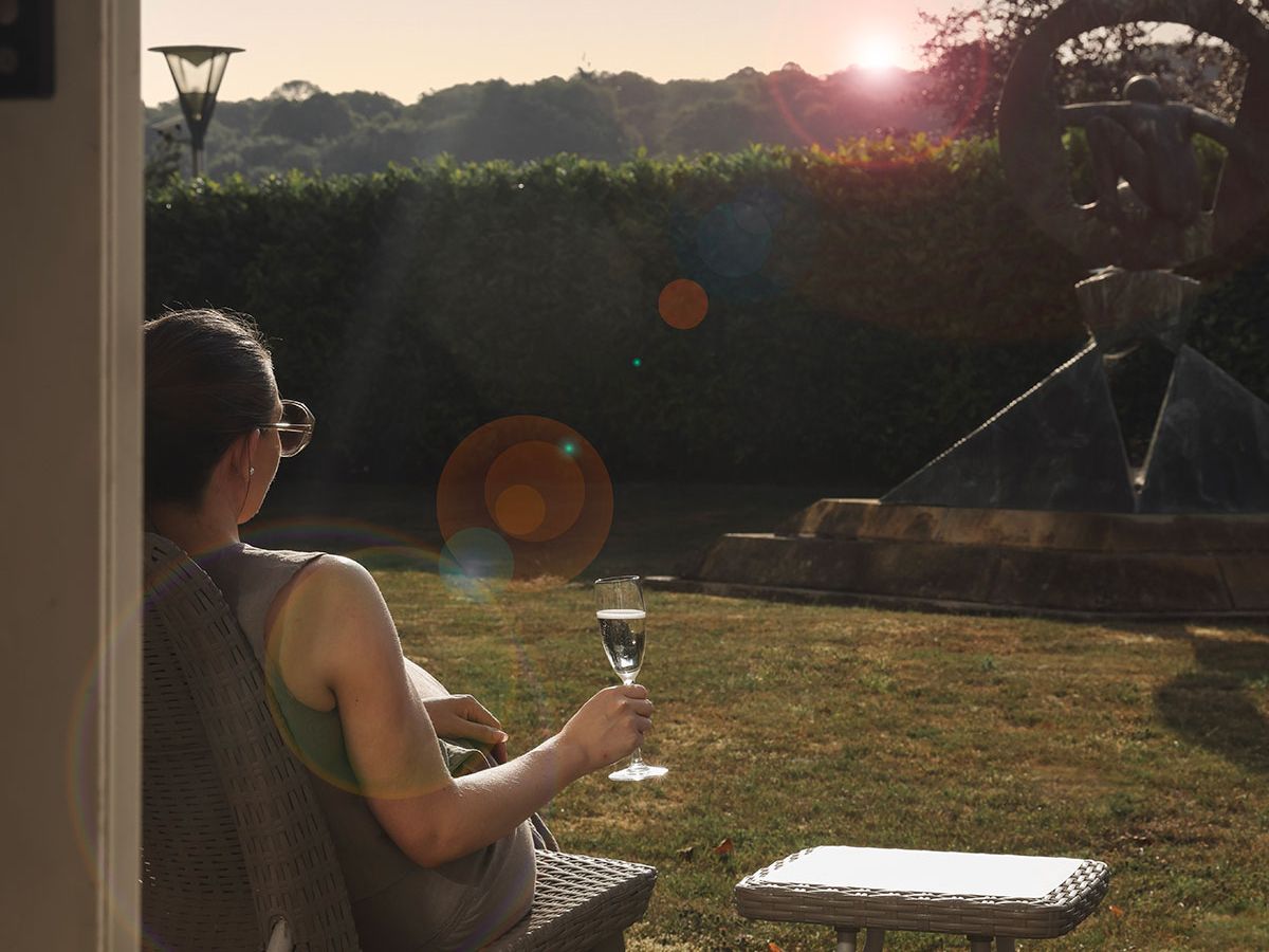 Woman relaxing in a garden chair with a glass of sparkling wine at sunset