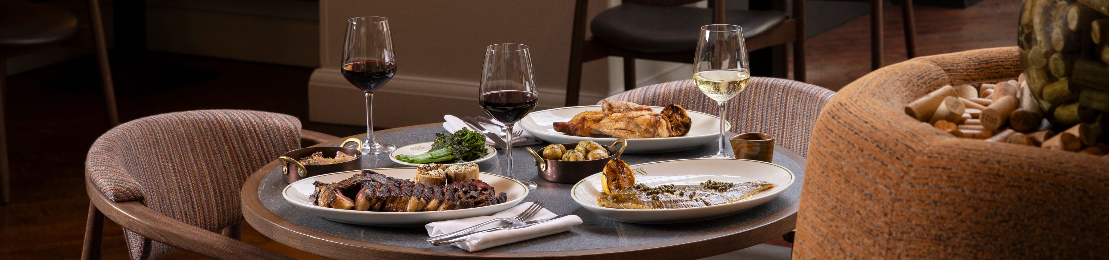Cosy restaurant dining table set with wine glasses and plated dishes in a warmly lit interior