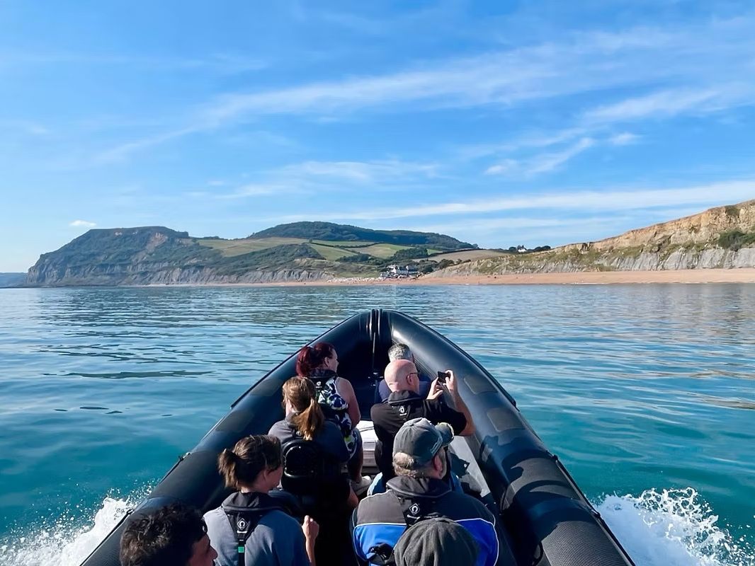Group of people on a speedboat enjoying scenic coastal views with cliffs and blue water