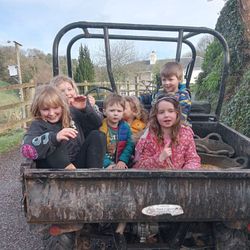 A group of young children ride in the back of a farm utility vehicle.