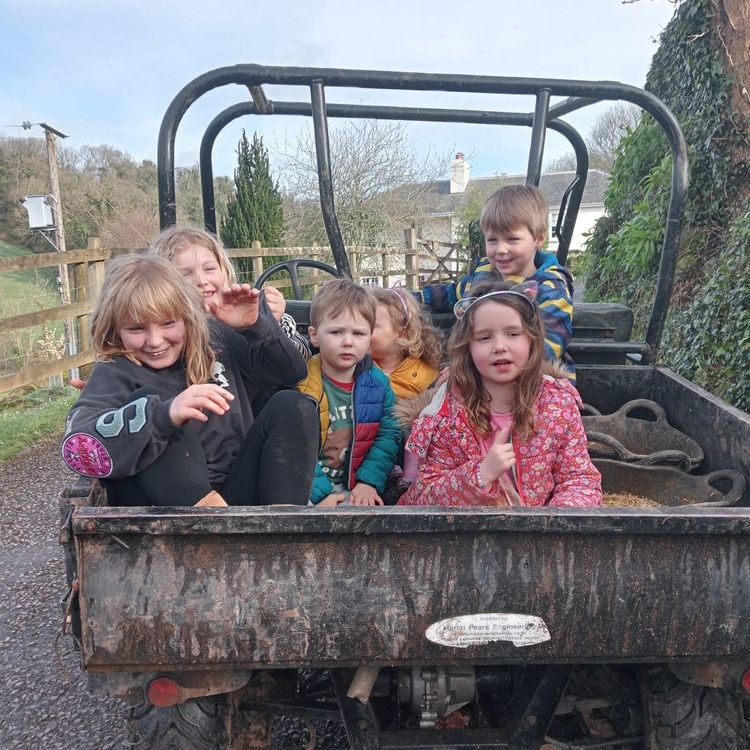 A group of young children ride in the back of a farm utility vehicle.