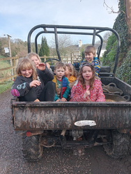 A group of young children ride in the back of a farm utility vehicle.