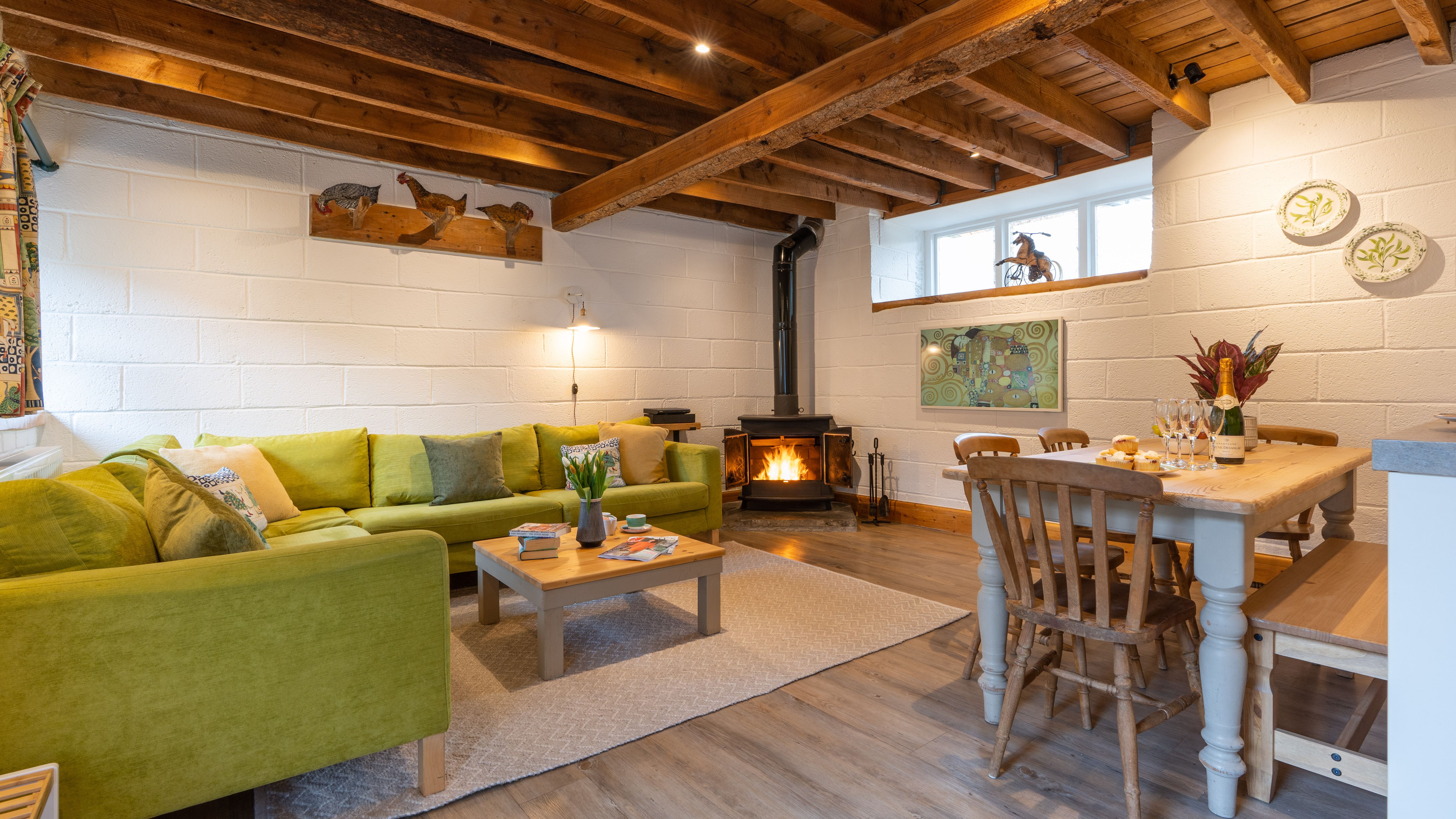 Stalls living area with green sofa and wood burner
