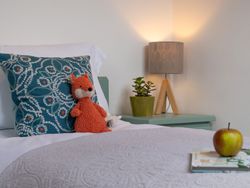 Soft toy, book and apple on bed