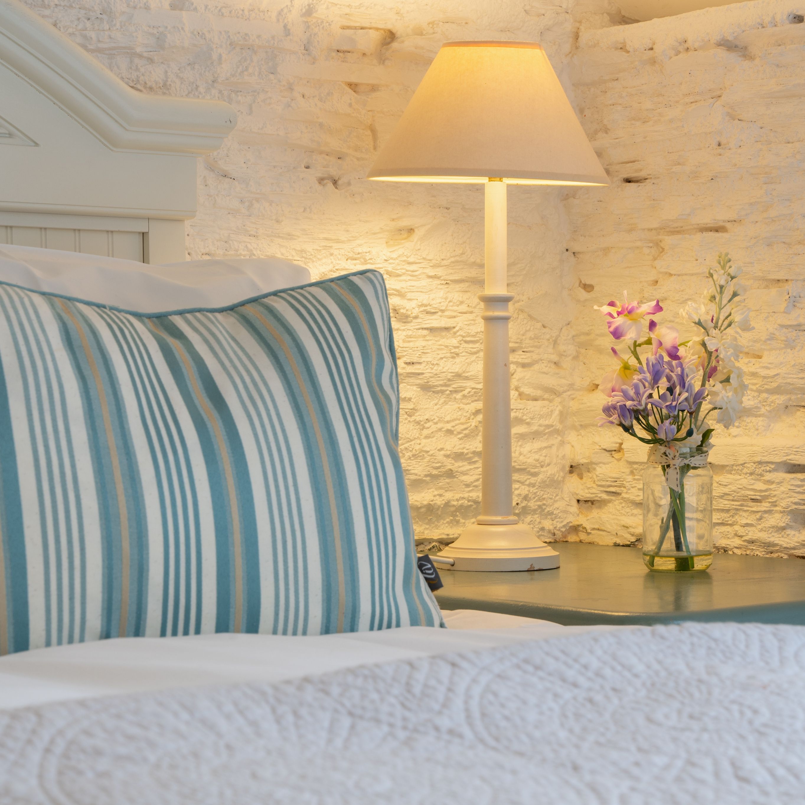 Detail photo of the bed in the dairy with small vase of flowers
