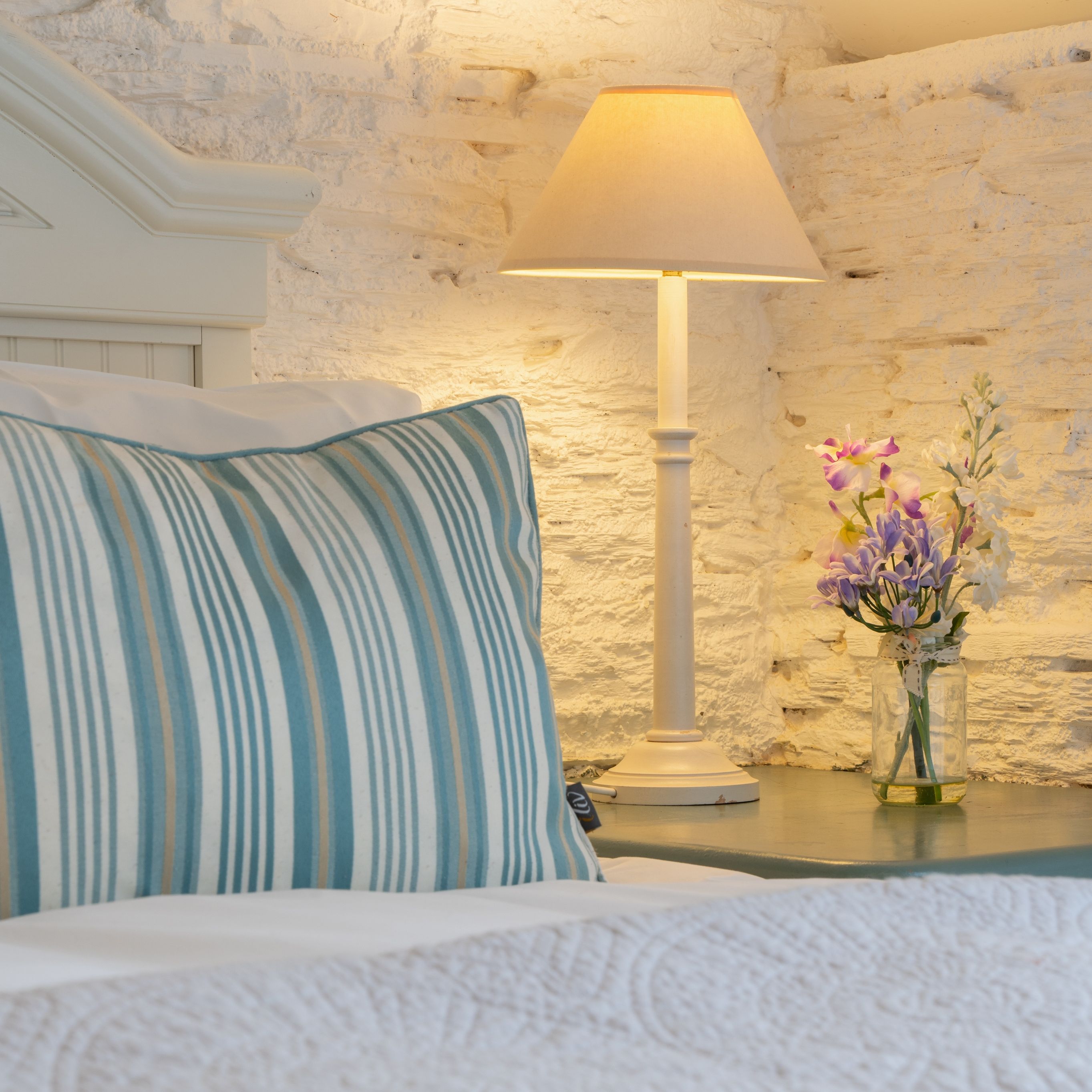 Detail photo of the bed in the dairy with small vase of flowers