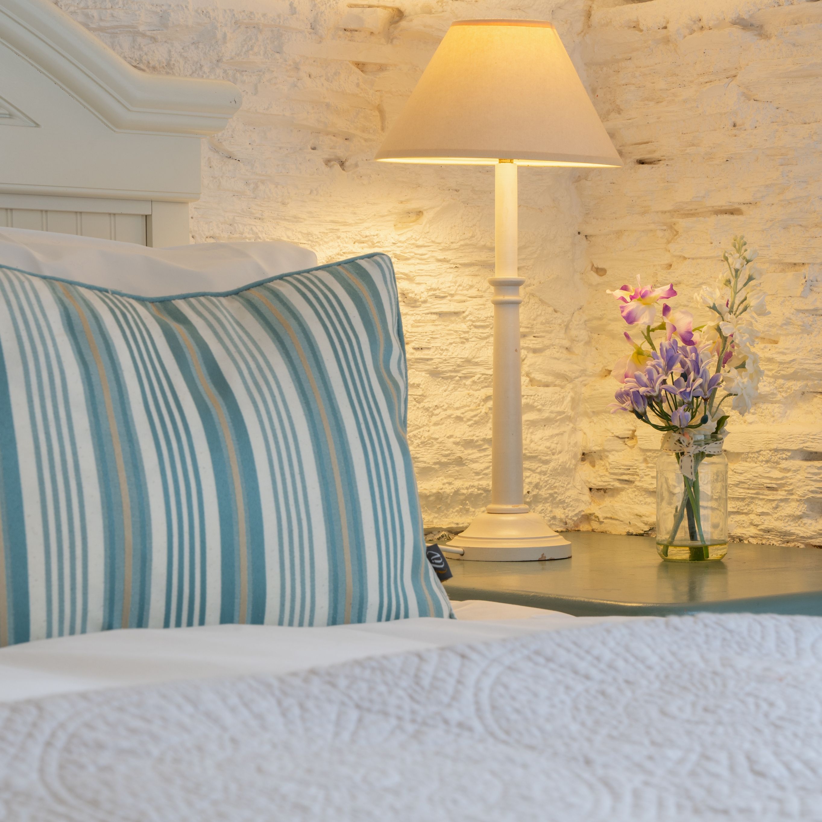 Detail photo of the bed in the dairy with small vase of flowers