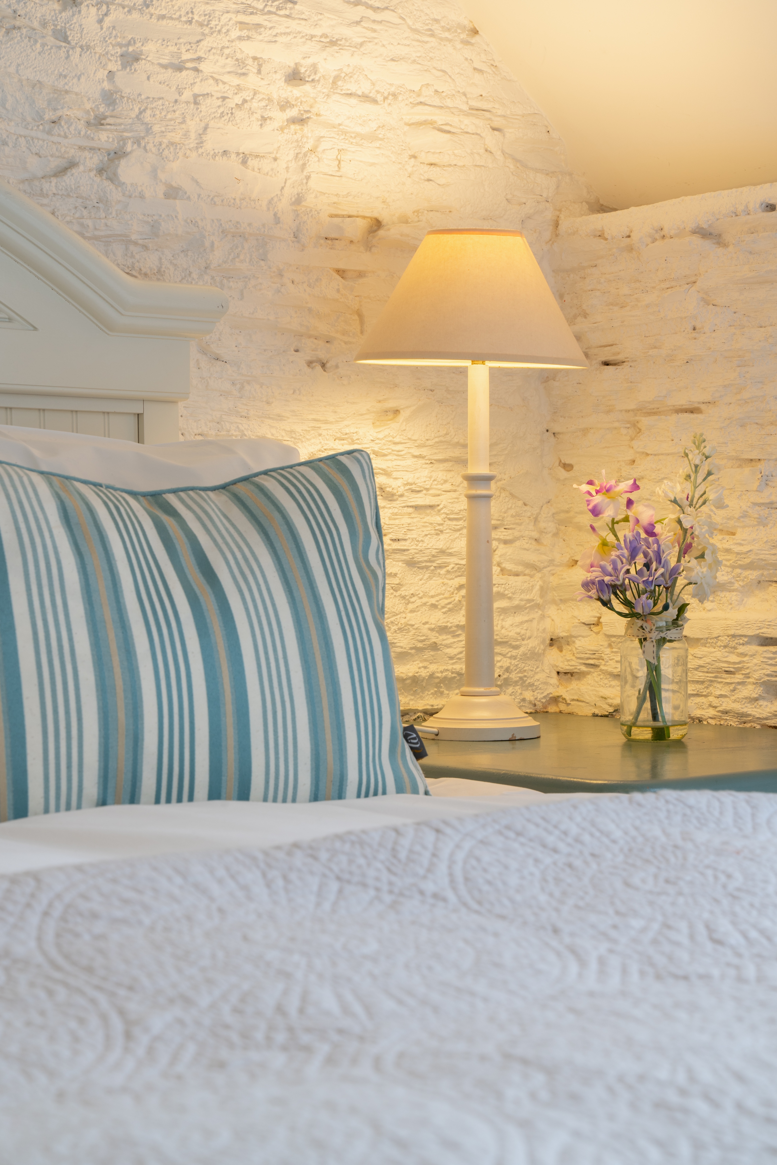 Detail photo of the bed in the dairy with small vase of flowers