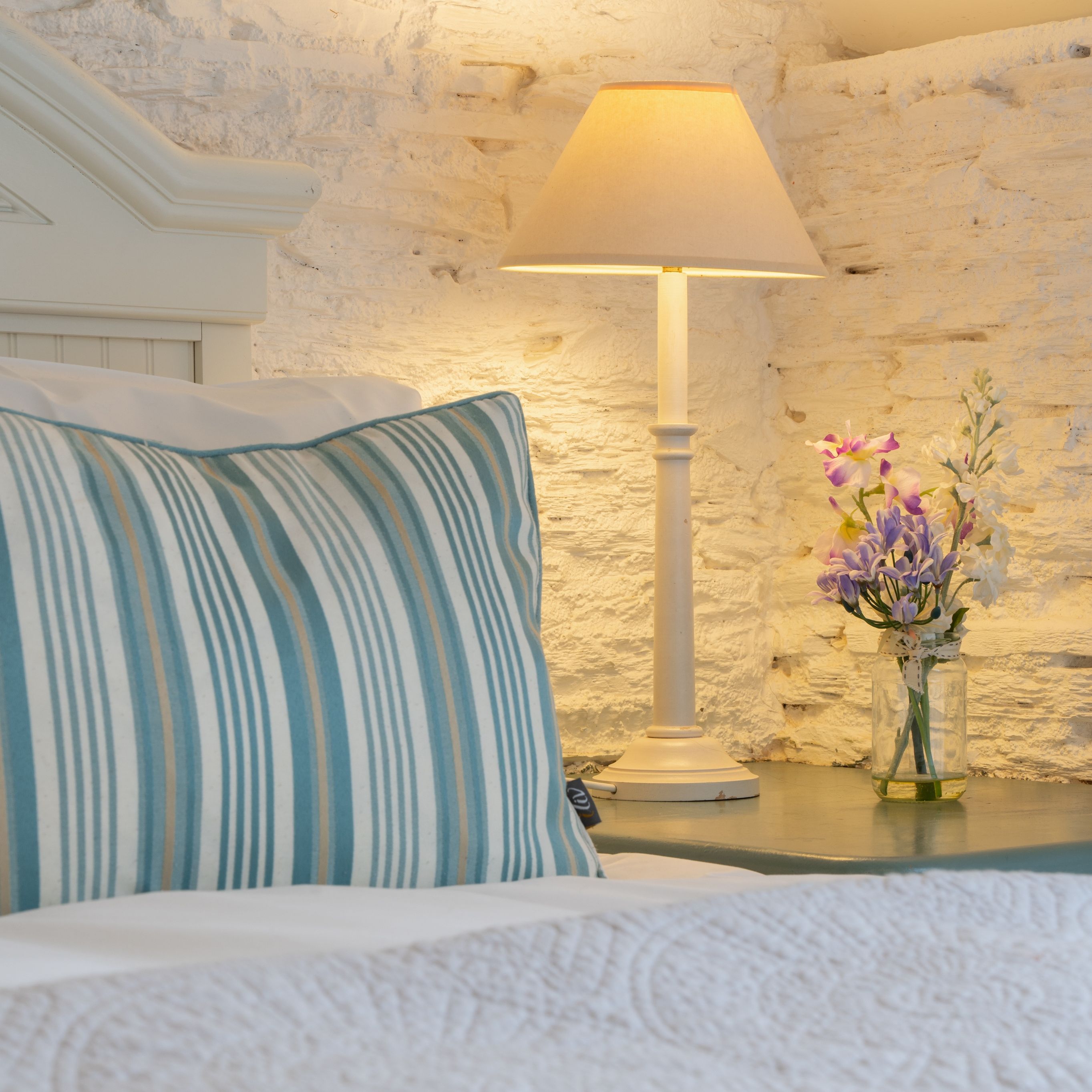 Detail photo of the bed in the dairy with small vase of flowers