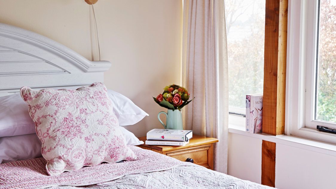 Floral bedhseets with vase of flowers on the bedside table