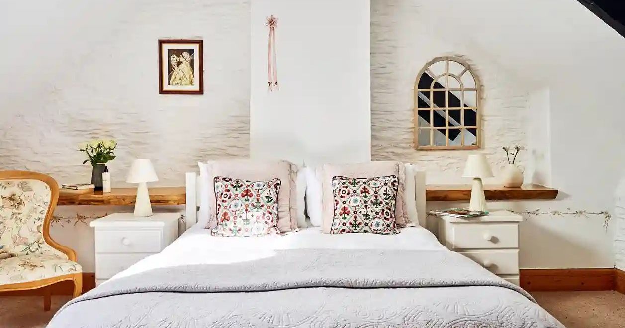 Front-facing view of the master bedroom in 1843 at Flear Farm Cottages, with floral cushions, quilted bedding, and soft rustic details.