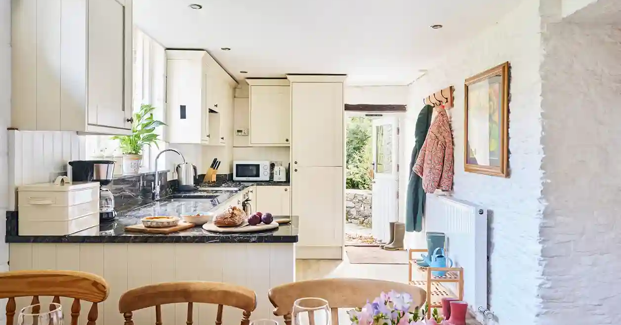 Kitchen and dining area in the Granary at Flear Farm Cottages, with cream cabinetry, granite worktops, rustic beams, and a table set for guests.
